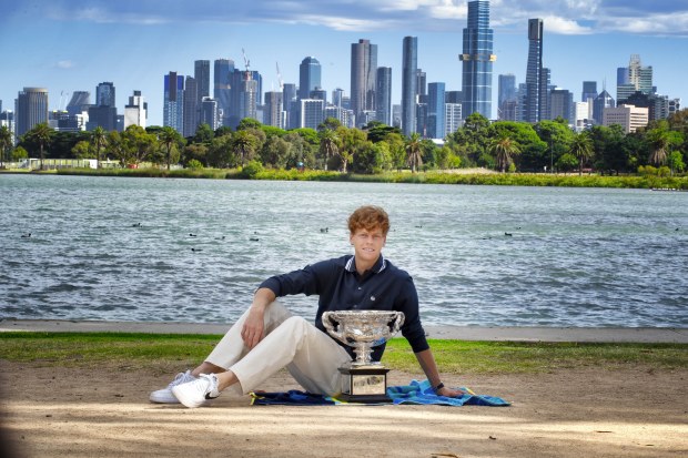 Jannik Sinner celebrates with the Australian Open trophy along the Yarra River.