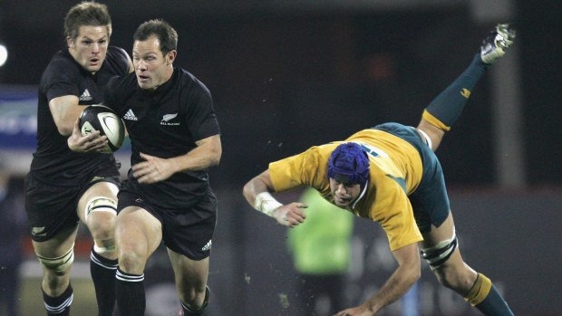 Leon MacDonald of the All Blacks leaves Nathan Sharpe of the Wallabies in his wake.