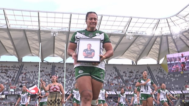 Harata Butler places a photo of former teammate Kath Wharton on the half way line ahead of the All Stars clash in Sydney.