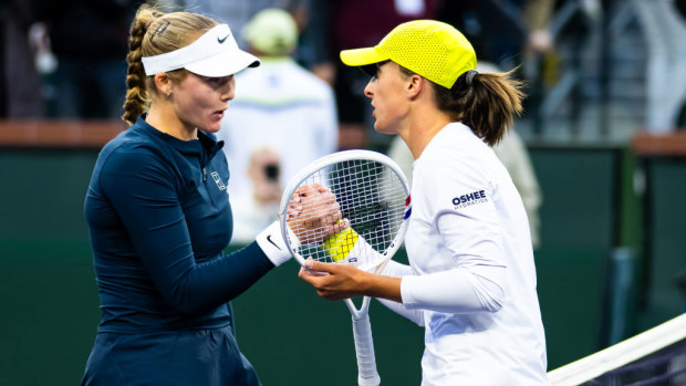 Mirra Andreeva and Iga Swiatek shake hands at the net.