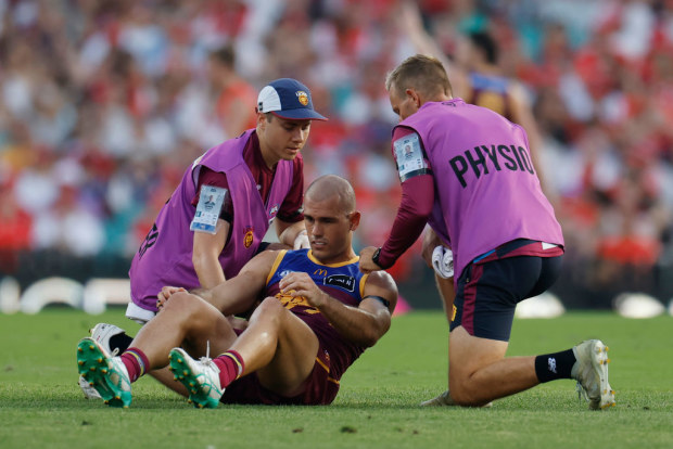 Brandon Starcevich of the Lions is assisted by medical staff.