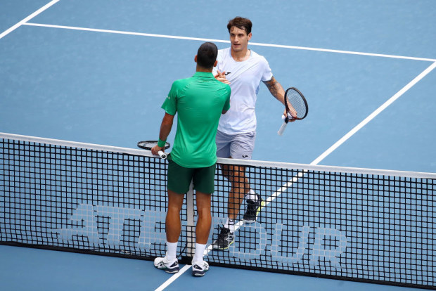 Camilo Ugo Carabelli of Argentina meets Novak Djokovic of Serbia at the net.