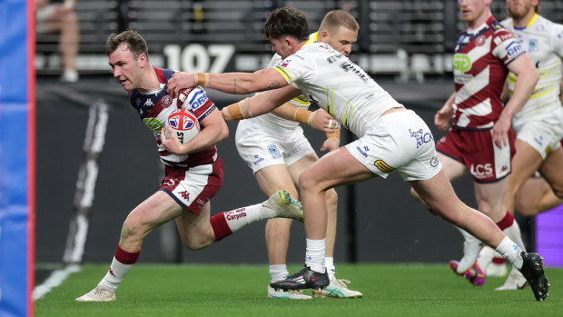 Harry Smith of the Wigan Warriors runs past Jordy Crowther of the Warrington Wolves to score a try.