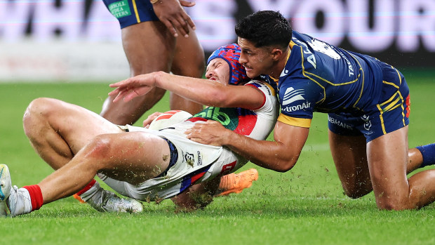 Kalyn Ponga of the Knights is tackled by Dylan Brown.