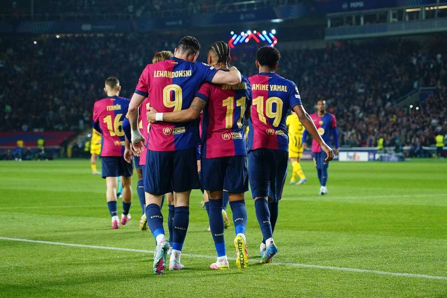 Robert Lewandowski celebrates scoring for Barcelona against Dortmund with Raphinha and Lamine Yamal.