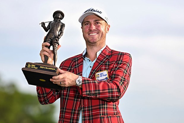 Justin Thomas smiles with the tournament trophy and plaid tartan jacket after his playoff victory in the final round of the RBC Heritage.