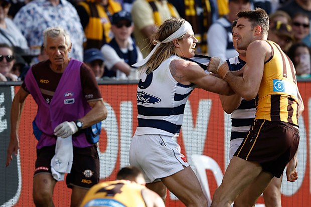 Conor Nash of the Hawks and Bailey Smith of the Cats wrestle as Jarman Impey of the Hawks falls to the ground.