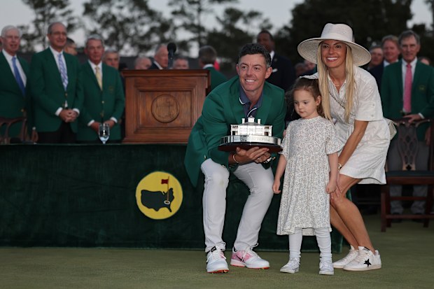 Rory McIlroy of Northern Ireland poses with daughter Poppy and wife Erica Stoll holding the Masters trophy during the Green Jacket Ceremony after winning the 2025 Masters Tournament at Augusta National Golf Club on April 13, 2025 in Augusta, Georgia. (Photo by Michael Reaves/Getty Images)