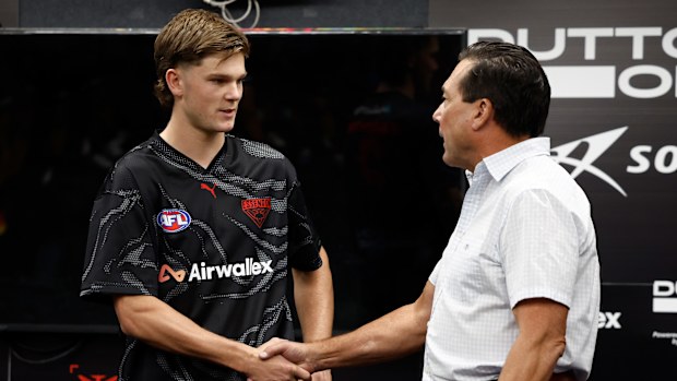 Jacob Farrow of the Bombers receives his Essendon jumper on debut from Gary O'Donnell.