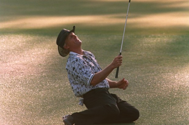 Greg Norman collapses on the ground after narrowly missing his chip shot on the 15th green.