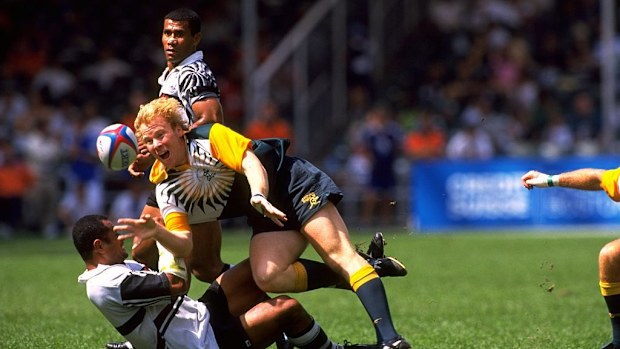 An Australian player is thrown to the ground by a Fijian player in the 1998 Hong Kong Rugby Sevens.