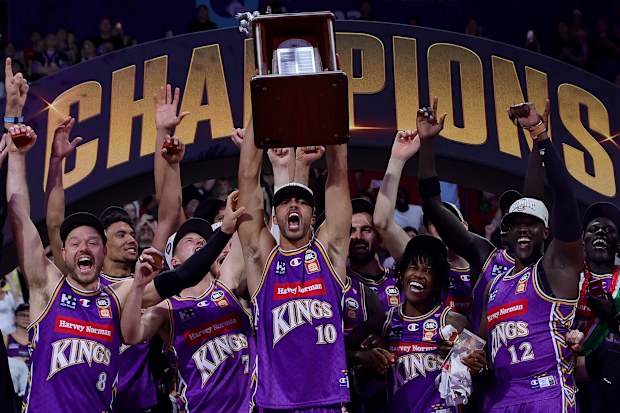 SYDNEY, AUSTRALIA - APRIL 05: Xavier Cooks of the Kings holds the NBL Championship trophy aloft after winning game five of the NBL Grand Final series between Sydney Kings and Adelaide 36ers at Qudos Bank Arena, on April 05, 2026, in Sydney, Australia. (Photo by Sarah Reed/Getty Images)